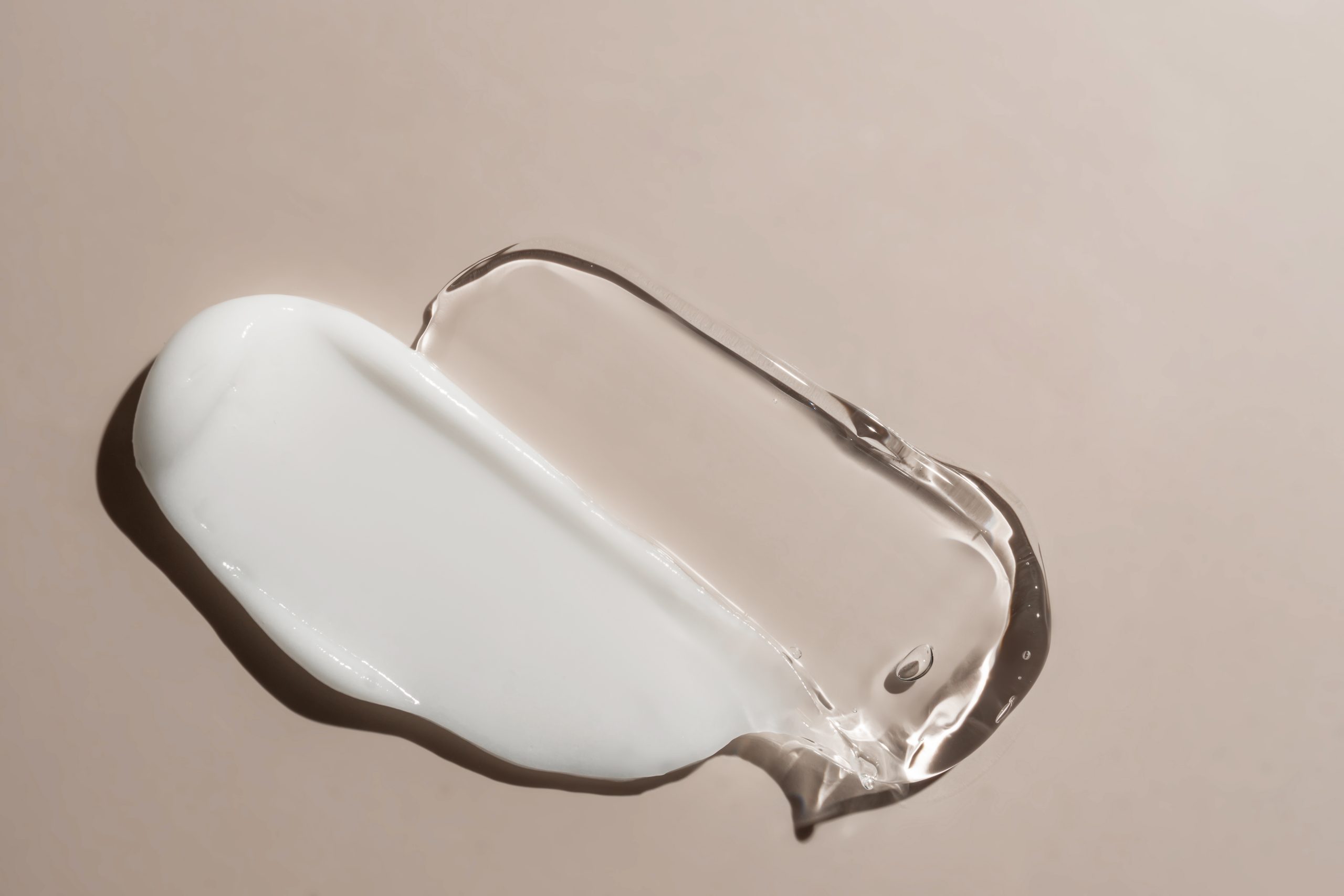 liquid cream and gel cosmetic smudge drops texture on beige background. cosmetic smears cream texture. skin care product stroke flat lay, cream with hyaluronic acid