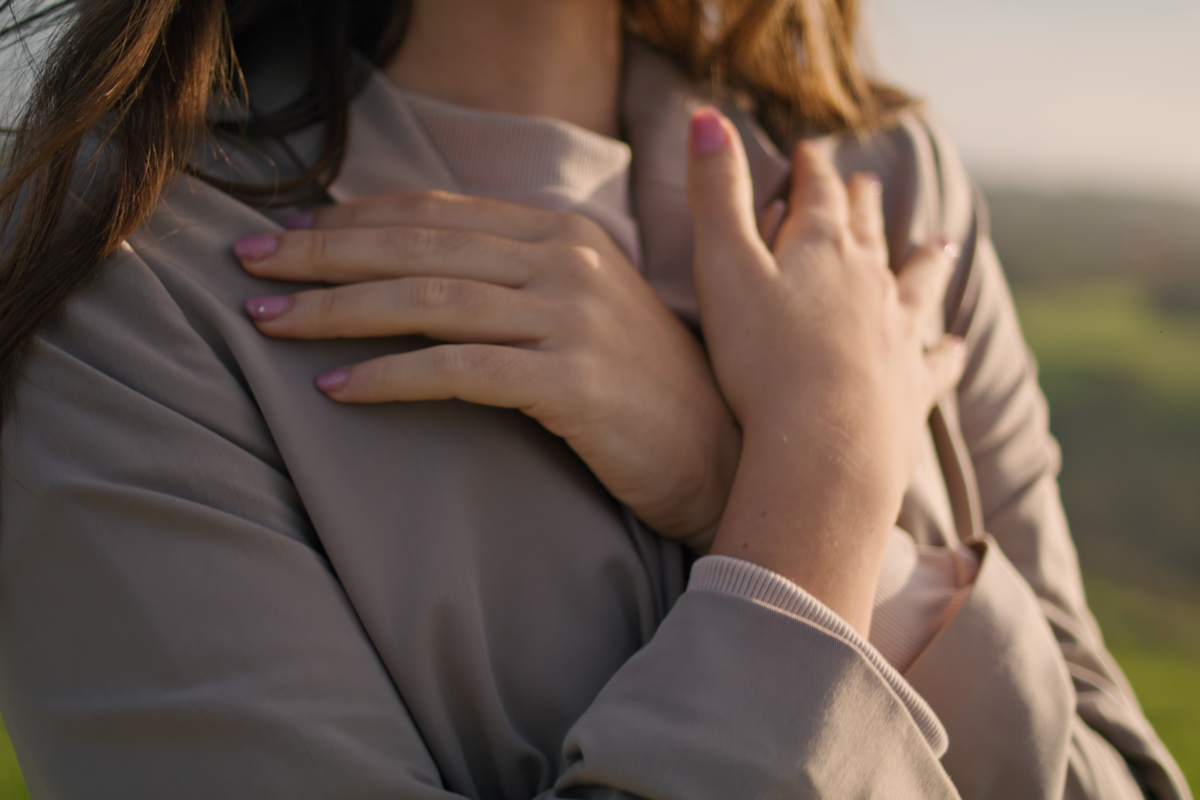 Woman placing hands on chest in a gesture of breast self-care and self-respect