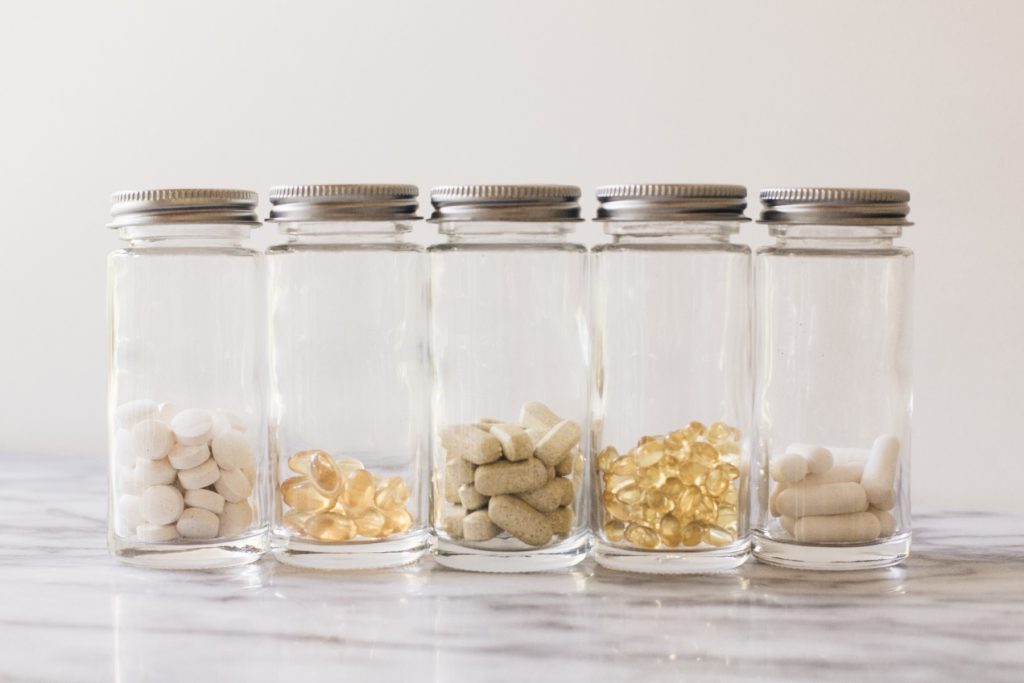 Daily herbal wellness supplements and vitamins in clear glass jars on a marble counterDaily herbal wellness supplements and vitamins in clear glass jars on a marble counter