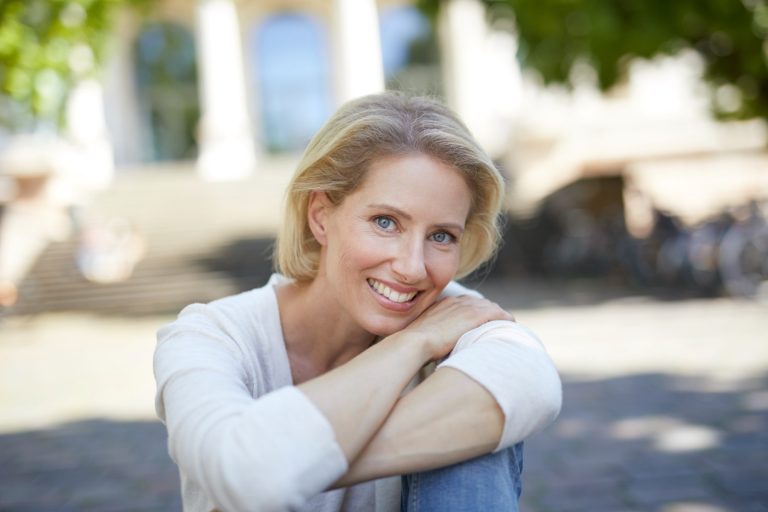 Healthy midlife woman smiling outdoors in natural light representing graceful aging
